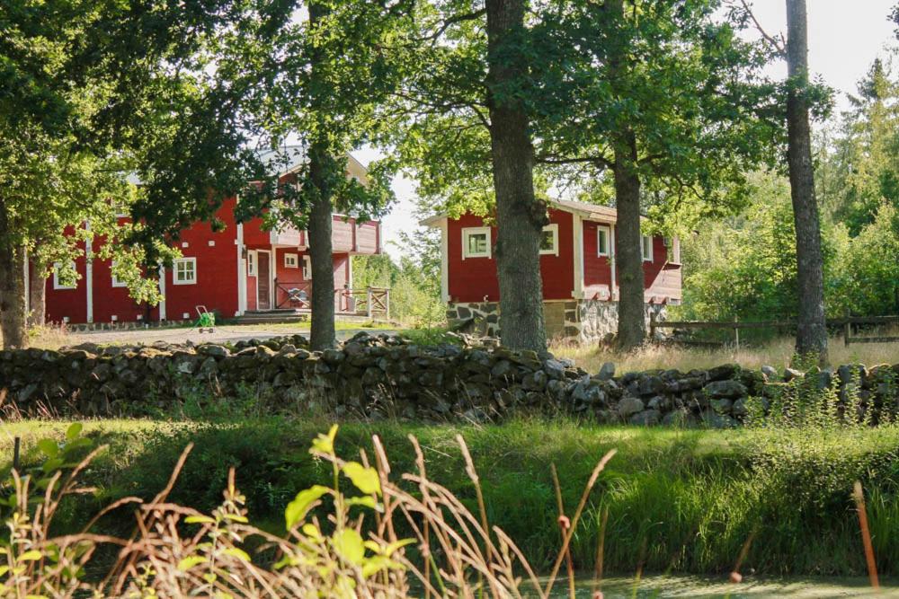 a red house with a stone wall and trees at Bergakungen Stugby in Osby