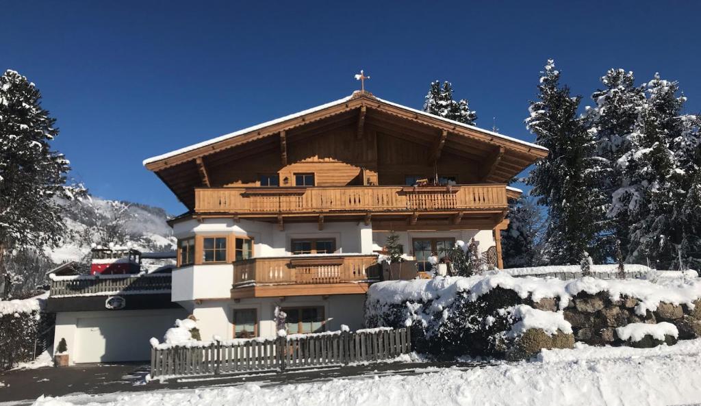 ヴェステンドルフにあるAppartement Margarethaの雪の中にバルコニーが付いた大きな木造の家
