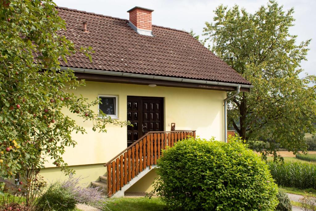 a small yellow house with a wooden staircase at Ernas Ferienhaus in Aschbach bei Fürstenfeld