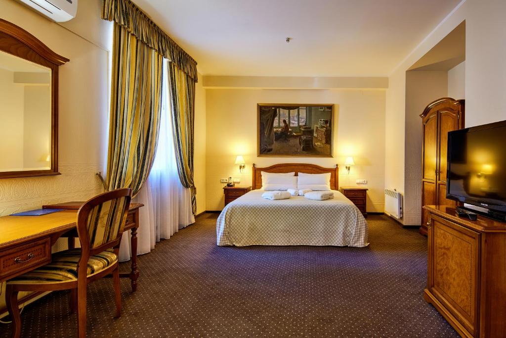 ドニプロにあるArt Hotel Academyのベッド、デスク、テレビが備わるホテルルームです。
