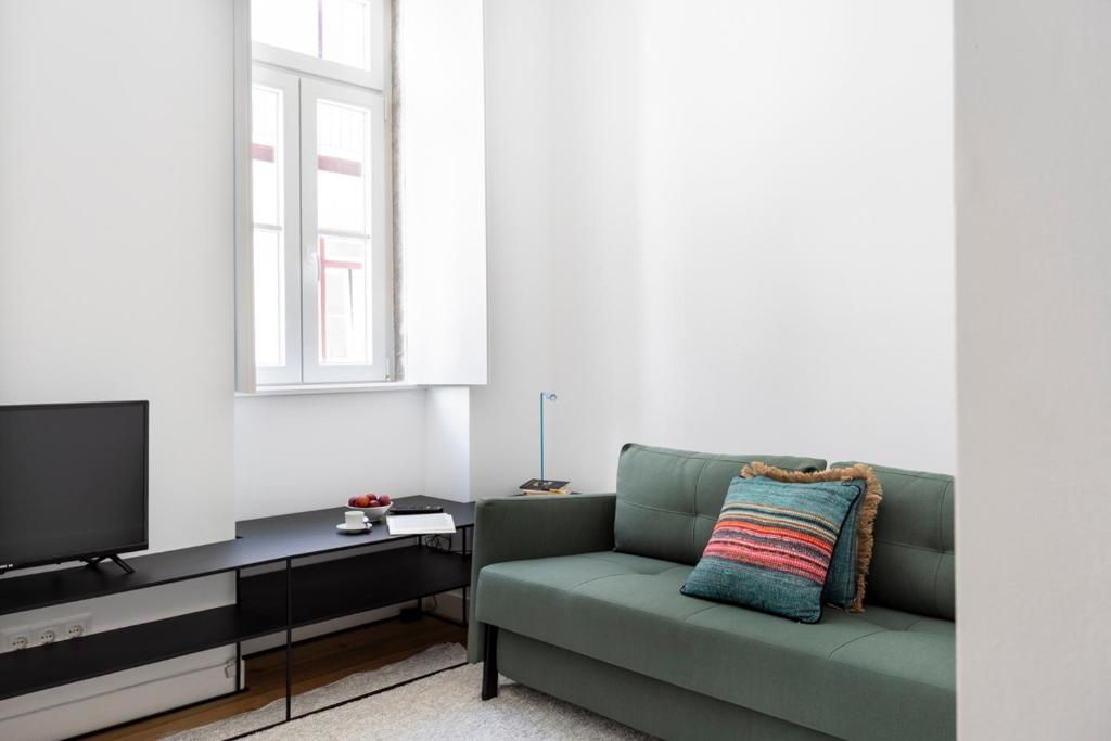 a living room with a green couch and a tv at FLH Vila Rosário Cosy Flat I in Lisbon