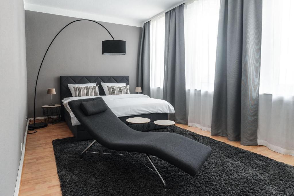 a bedroom with a bed and a black chair at Stylisches Münster City-Apartment 83 m² in Münster