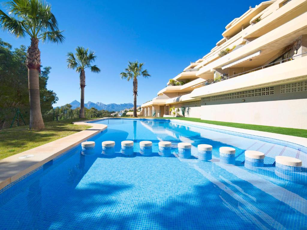 - une piscine à côté d'un bâtiment avec des palmiers dans l'établissement Apartment Villa Marina Golf-1 by Interhome, à Altea la Vieja