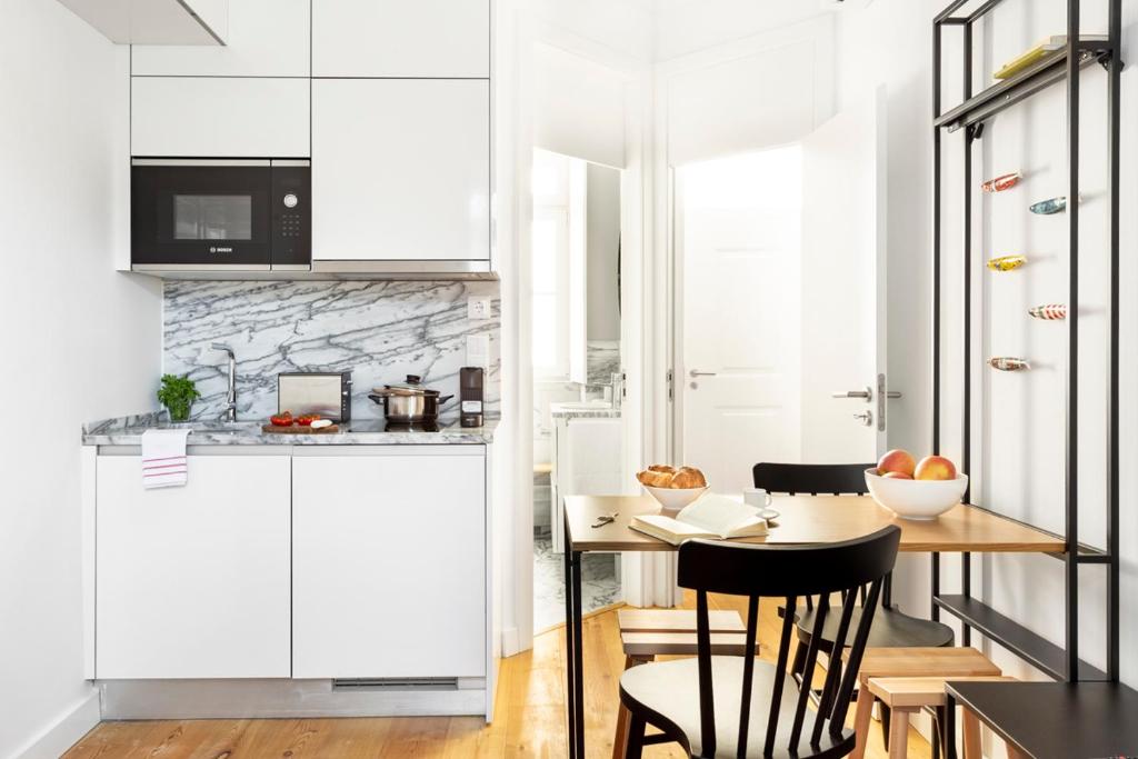 uma cozinha com armários brancos e uma mesa com cadeiras em FLH Vila Rosário Cosy Flat II em Lisboa