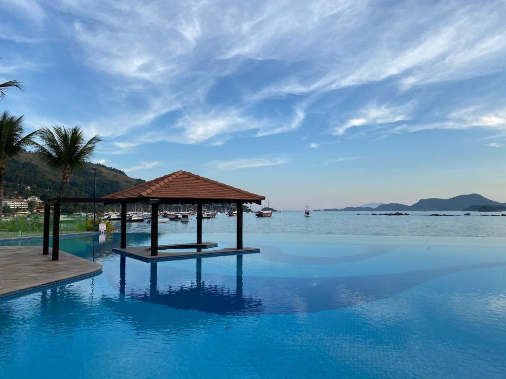 uma piscina com um gazebo e a água em Charme Comforto Beira Mar em Angra dos Reis