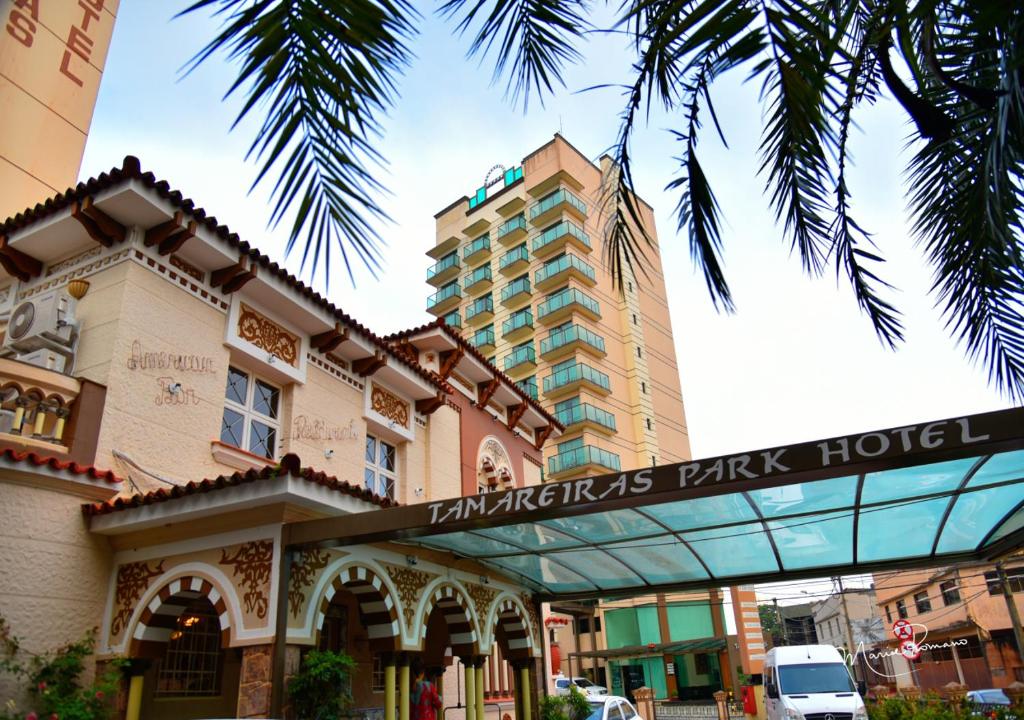 um hotel em frente a um edifício com uma palmeira em Tamareiras Park Hotel em Uberaba