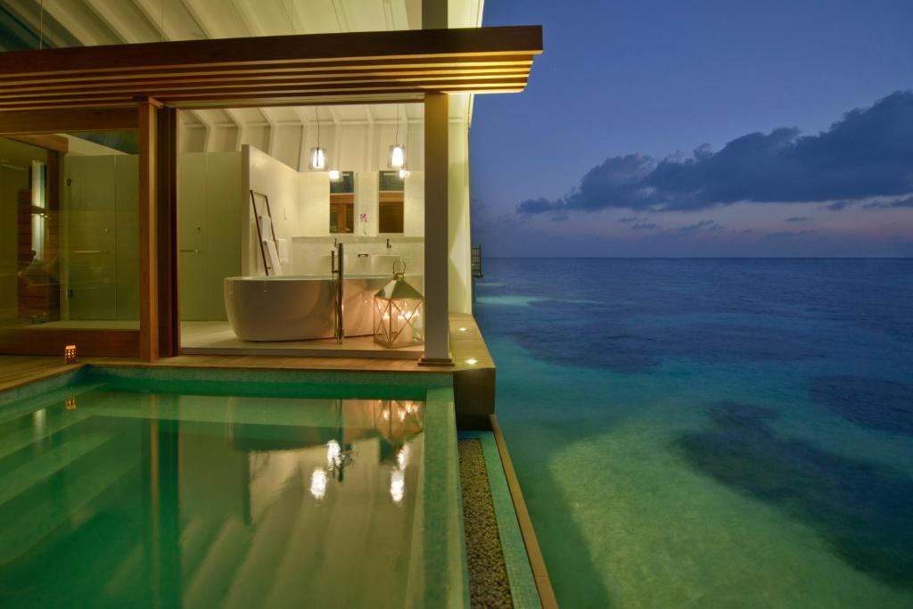 a bathroom with a bath tub next to the ocean at Kandolhu Maldives in Himandhoo 