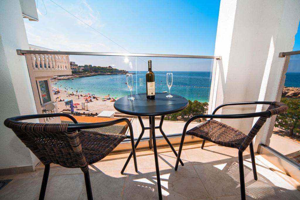 a table with a bottle of wine and two chairs at David Lux beach rooms in Dobra Voda