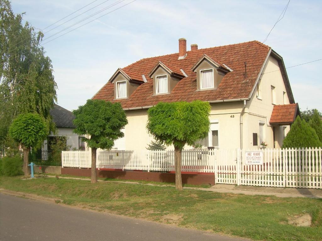 奥巴曹洛克Maya Vendégház的白色的房子,有白色的栅栏和树木