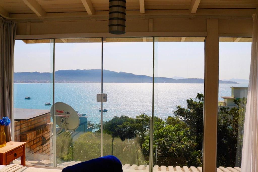 Habitación con ventanas de cristal y vistas al océano. en Sobrado Bela Vista, en Bombinhas