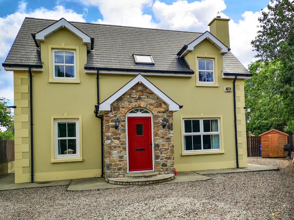 una casa amarilla con puerta roja en Holiday Cottages Portsalon, en Portsalon