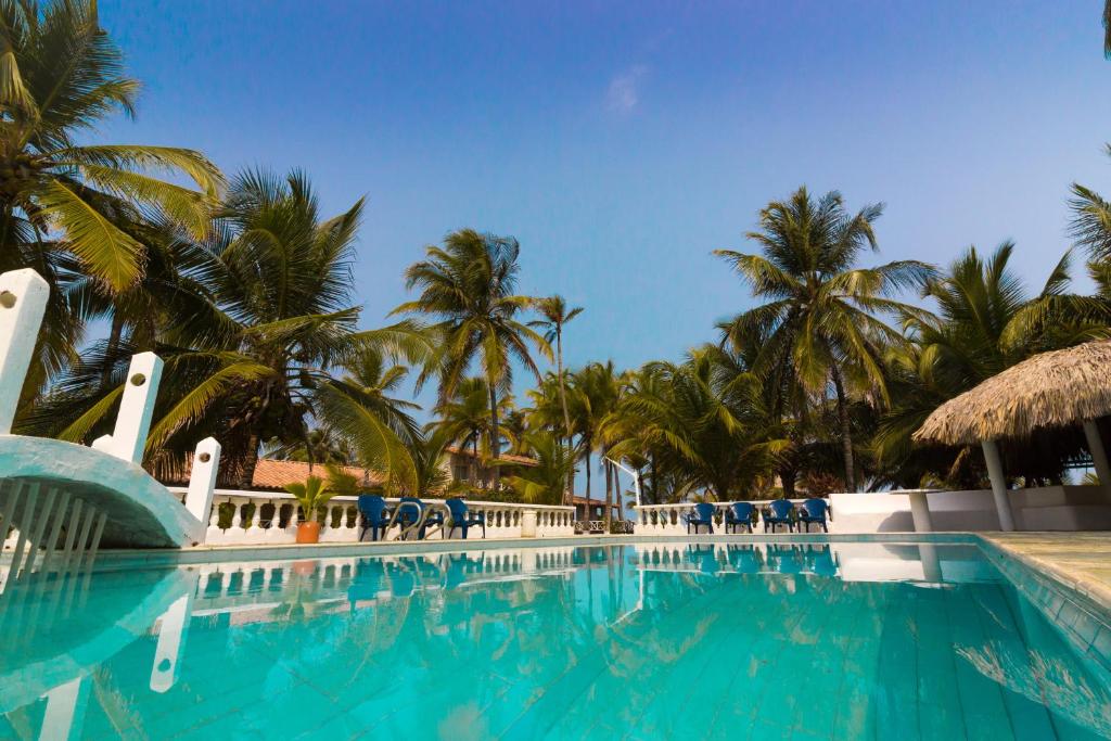 uma piscina com cadeiras azuis e palmeiras em Santa María de los Vientos em San Bernardo del Viento