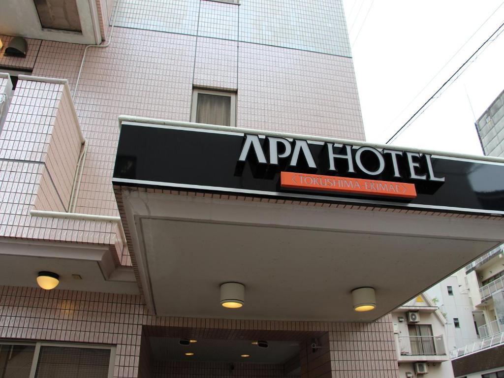 APA Hotel Tokushima Ekimae في توكوشيما: علامة على فندق ابان أمام مبنى