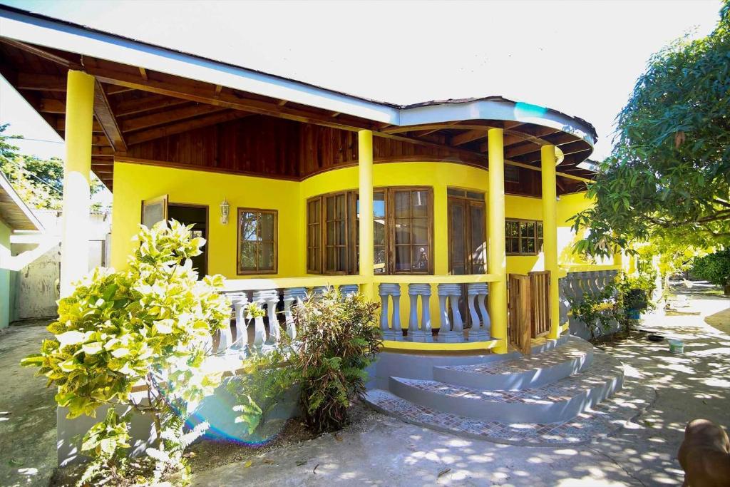 une maison jaune avec des escaliers devant elle dans l'établissement R&V VILLA, à Negril