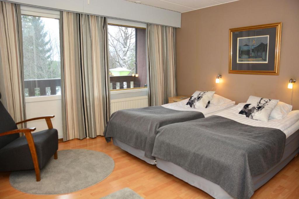 una habitación de hotel con 2 camas y una silla en Revontuli Resort Rooms, en Hankasalmi