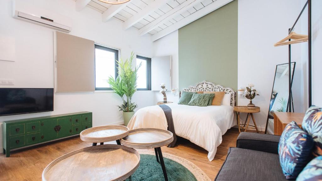 a bedroom with a bed and two tables and a tv at Lola de Triana Apartments in Seville