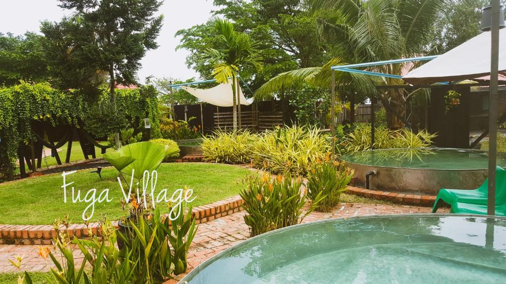 a pool in a garden with a table and chairs at Fuga Village BeachGetaway in Melaka