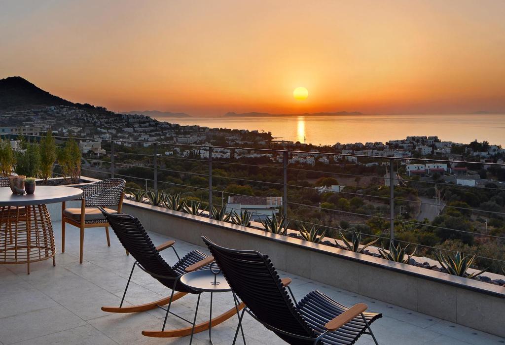 ein Balkon mit Stühlen und einem Tisch und einem Sonnenuntergang in der Unterkunft G Beyond Residences & Villas, Yalıkavak, Bodrum in Yalıkavak