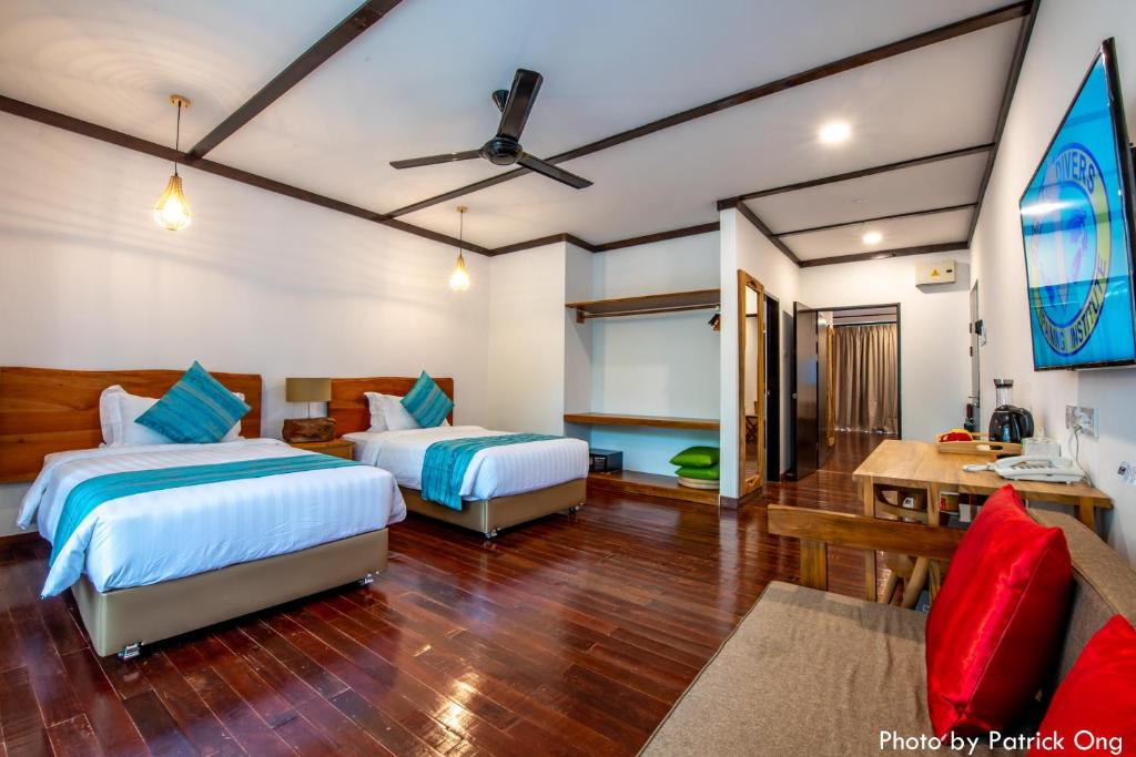 a bedroom with two beds and a table and a desk at Borneo Divers Mabul Resort in Pulau Mabul 