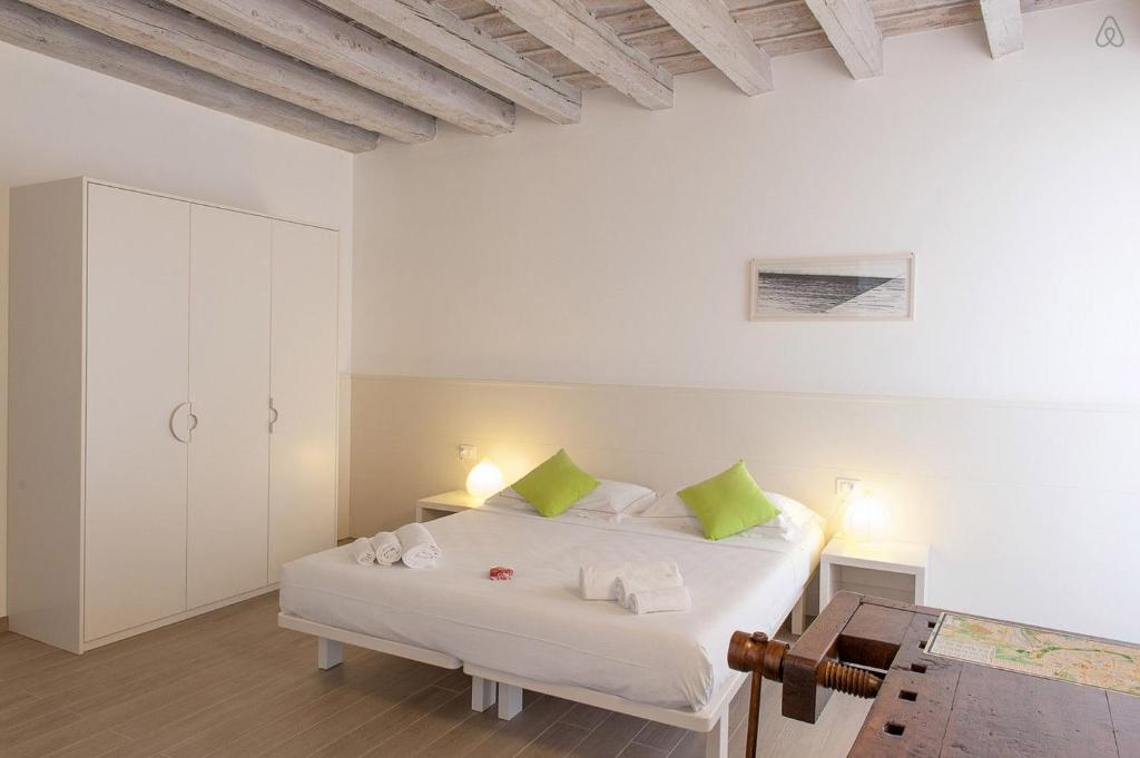 a white bedroom with a white bed with green pillows at Residenza Cardo Massimo in Verona