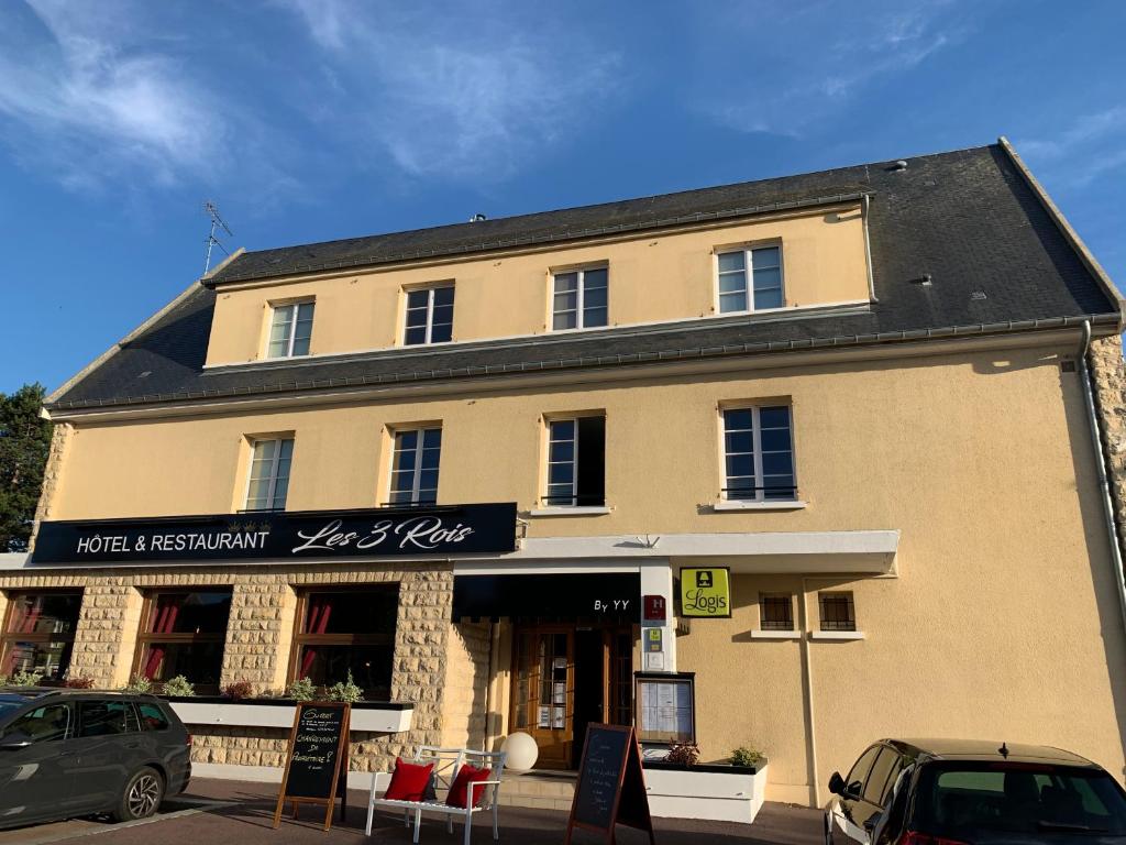 un grand bâtiment avec un panneau devant lui dans l'établissement Les 3 rois by YY, à Villers-Bocage