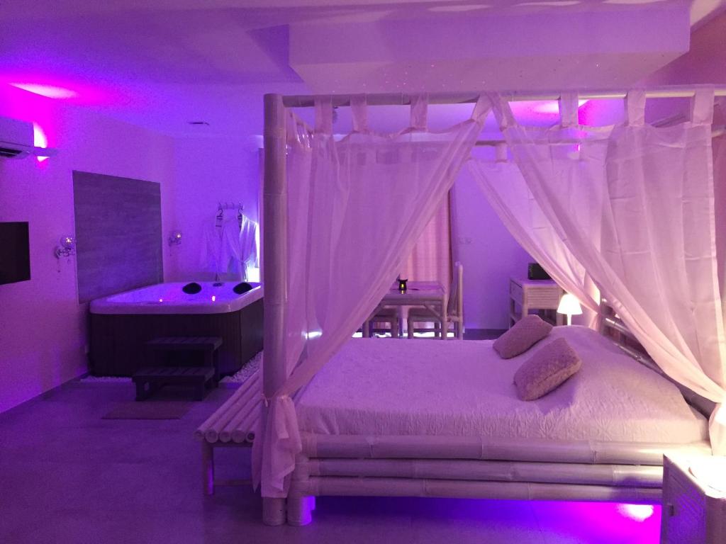 a bedroom with a bed and a tub in a room with purple lighting at La Paillote Exotique Spa in Beaucaire