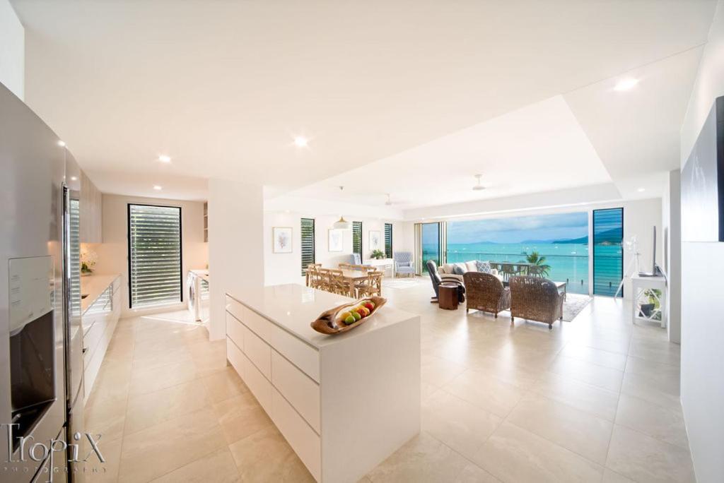 a kitchen and living room with a view of the ocean at Splendeur Sur La Mer - One Bedroom in Airlie Beach