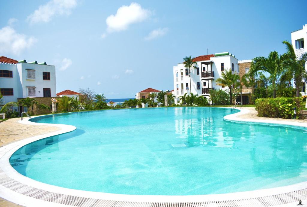 a large swimming pool with buildings in the background at Sultan Palace Beach Resort - AMANI Apartment CB2-202 in Kikambala