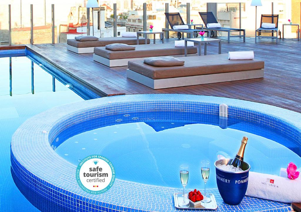 a swimming pool with a bottle of champagne and wine glasses at Axel Hotel Barcelona - Adults Only in Barcelona