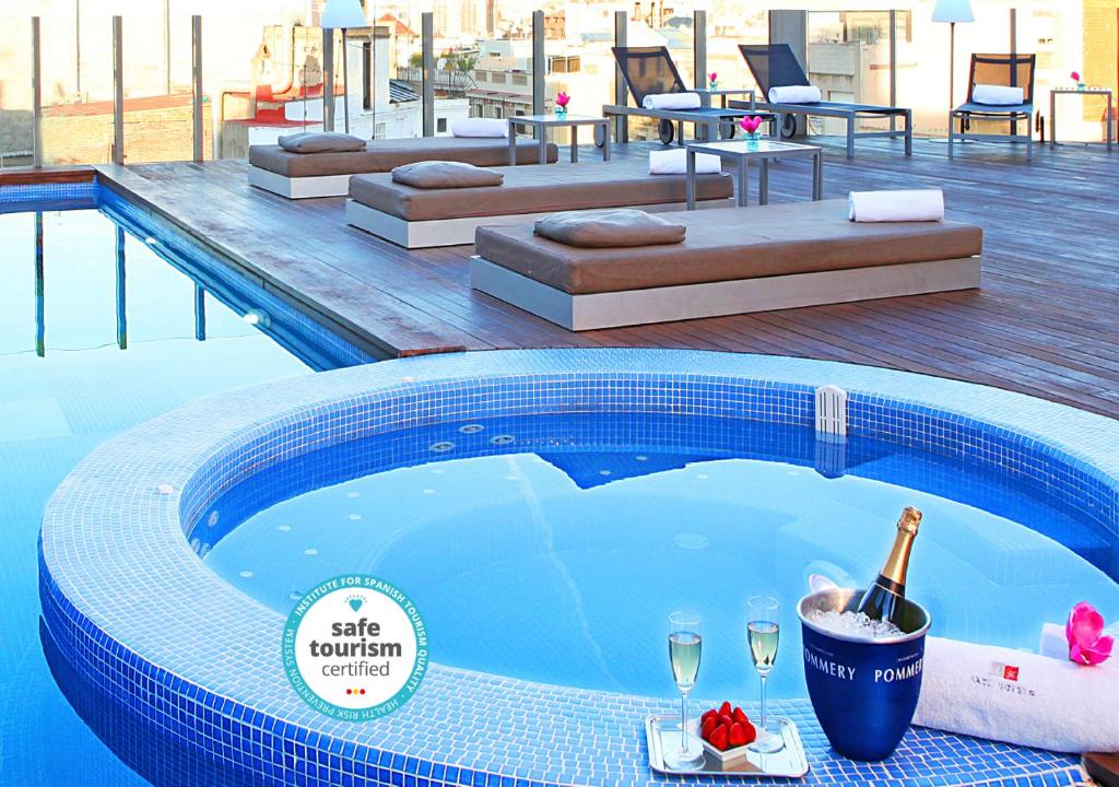 una piscina con una botella de champán y copas de vino en Axel Hotel Barcelona & Urban Spa- Adults Only, en Barcelona