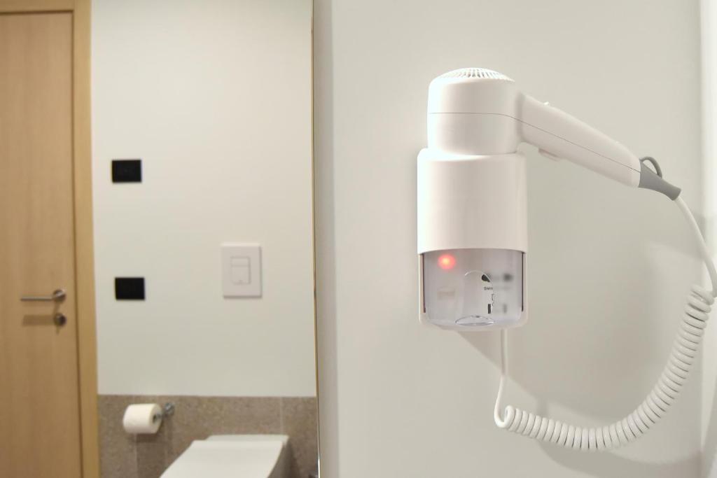 a white hair dryer in a bathroom with a mirror at Hotel Casa Del Pellegrino in Padova