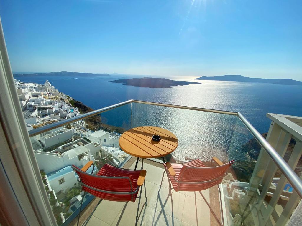 a table and chairs on a balcony with a view of the ocean at Panorama Boutique Hotel in Fira