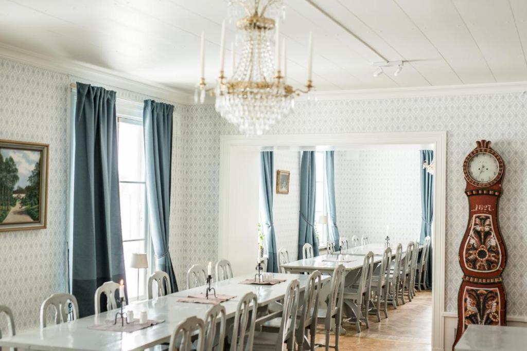 une salle à manger avec des tables, des chaises et une horloge dans l'établissement Snöå Bruk Hotell och konferens, à Dala-Järna