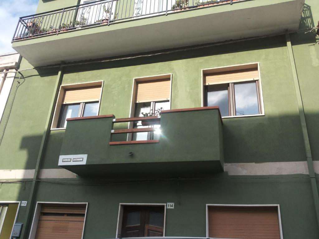 a green building with windows and a balcony at Casa Batti in Oristano