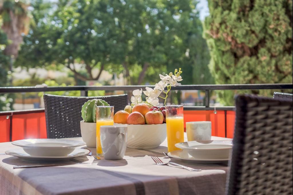 a table with a bowl of fruit and glasses of orange juice at Sur Suites Alhambra in Fuengirola
