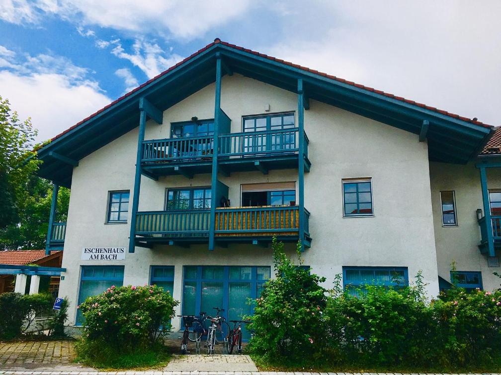 ein großes weißes Gebäude mit einem Balkon und Fahrrädern, die draußen geparkt sind in der Unterkunft Joseph's am Bach in Übersee