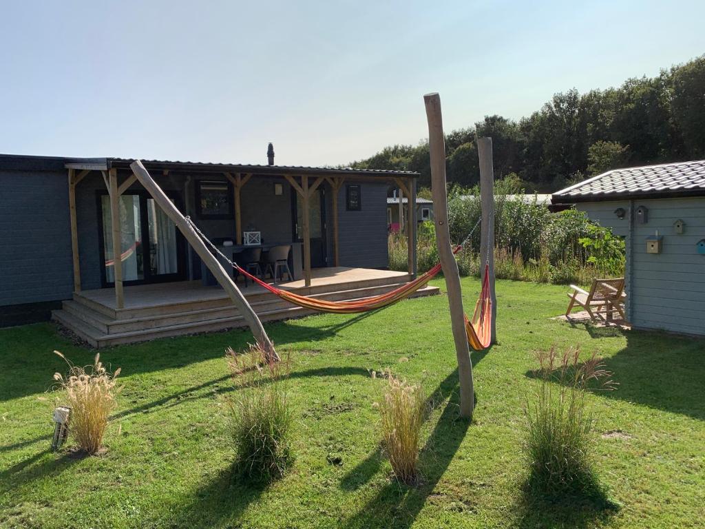 a yard with a hammock in front of a house at Luxe All season Chalet De Goudenregen in Balkbrug
