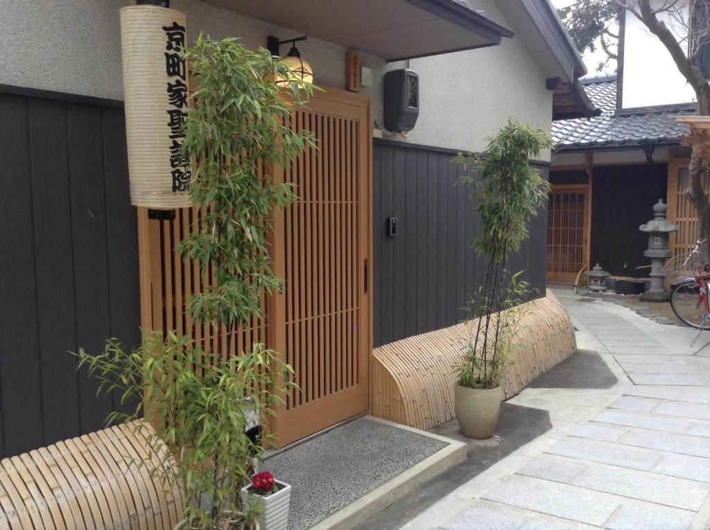 a gate to a house with two potted plants at Machiya Kyoto Shogoin in Kyoto