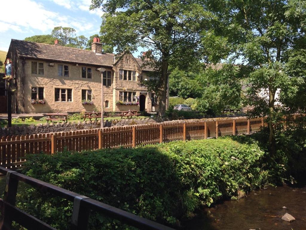 a house with a wooden fence next to a river at Pendle Inn in Barrowford