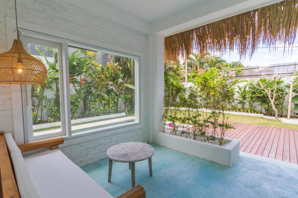 a room with a couch and a table and windows at Guru Canggu in Canggu