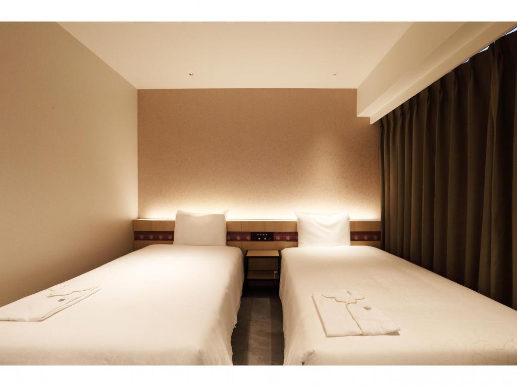 two beds sitting next to each other in a room at Henn na Hotel Premier Nara in Nara