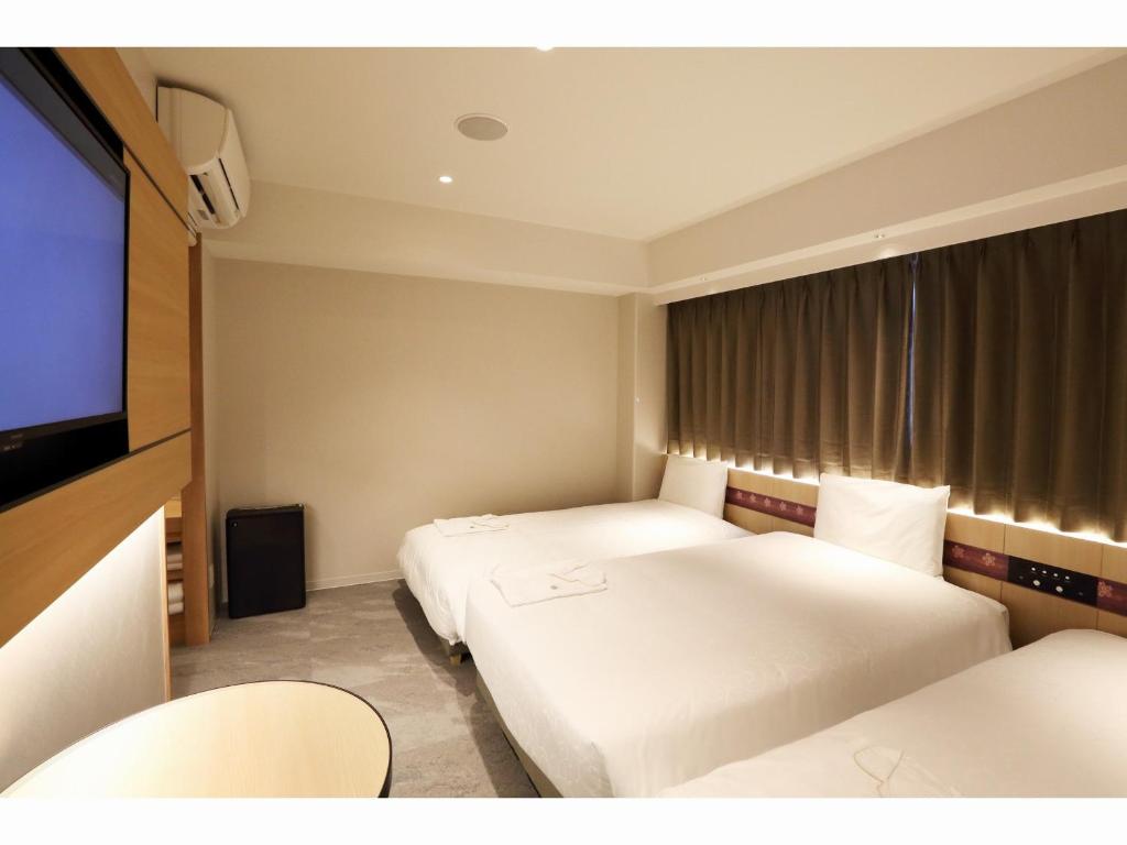 a hotel room with two beds and a flat screen tv at Henn na Hotel Premier Nara in Nara