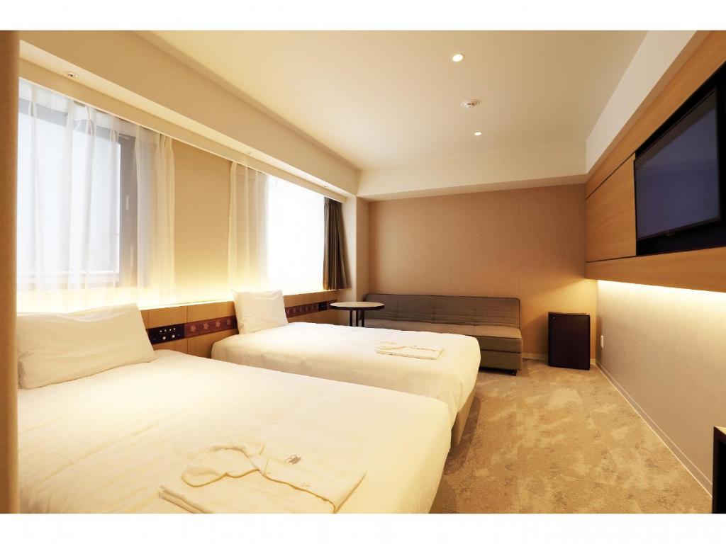 a hotel room with two beds and a flat screen tv at Henn na Hotel Premier Nara in Nara