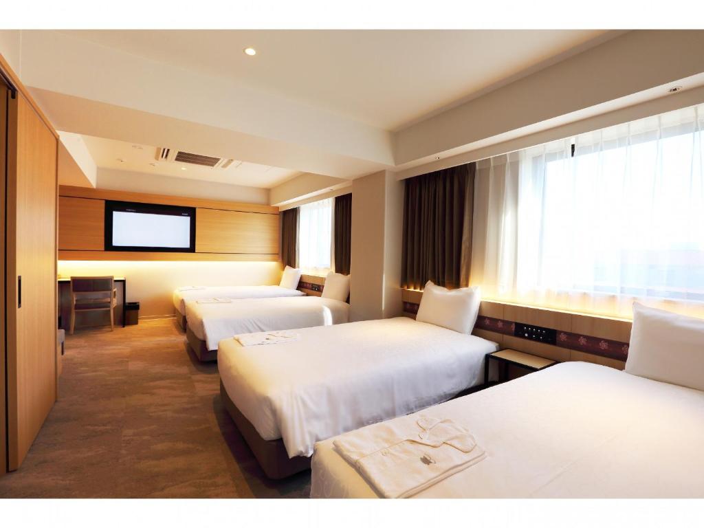 a hotel room with two beds and a television at Henn na Hotel Premier Nara in Nara