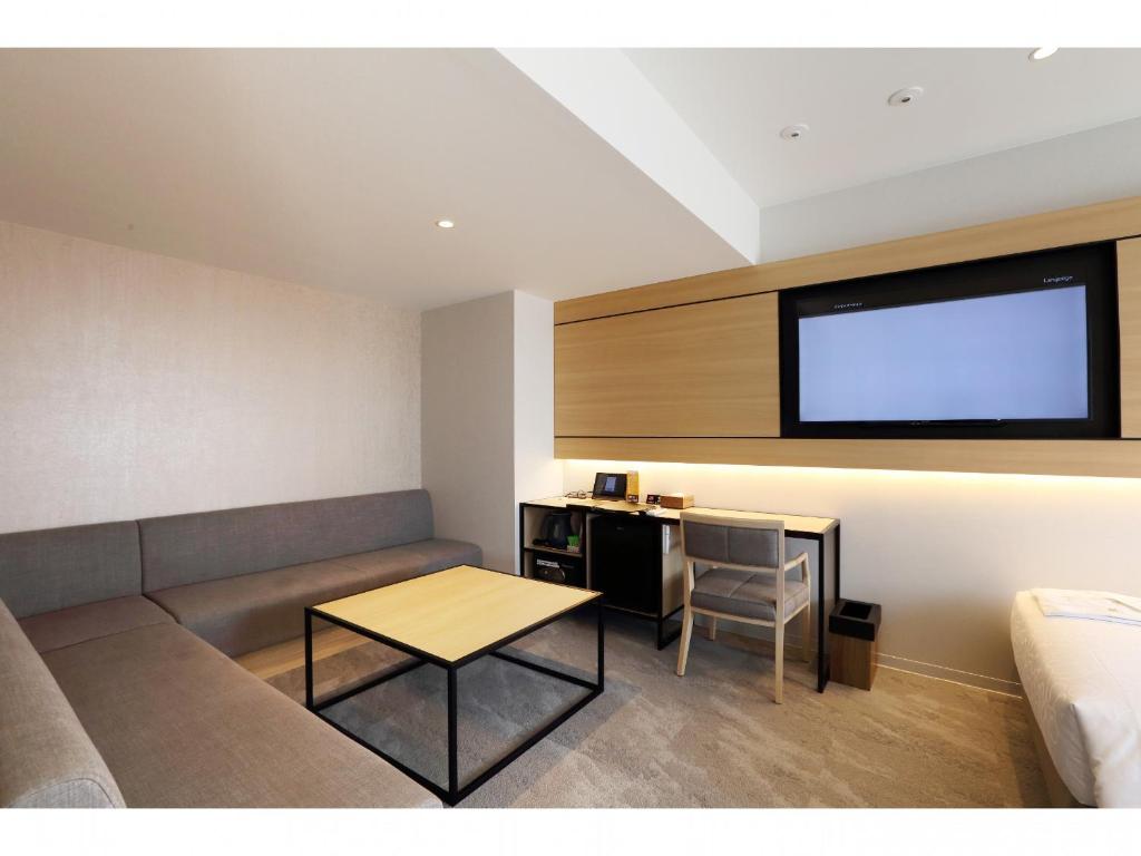 a living room with a couch and a table and a tv at Henn na Hotel Premier Nara in Nara