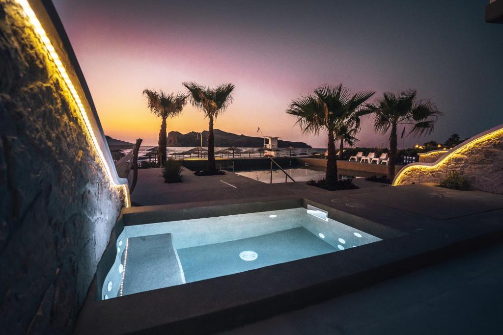 a small swimming pool on the side of a building with palm trees at Vergina Beach Hotel in Agia Marina Nea Kydonias