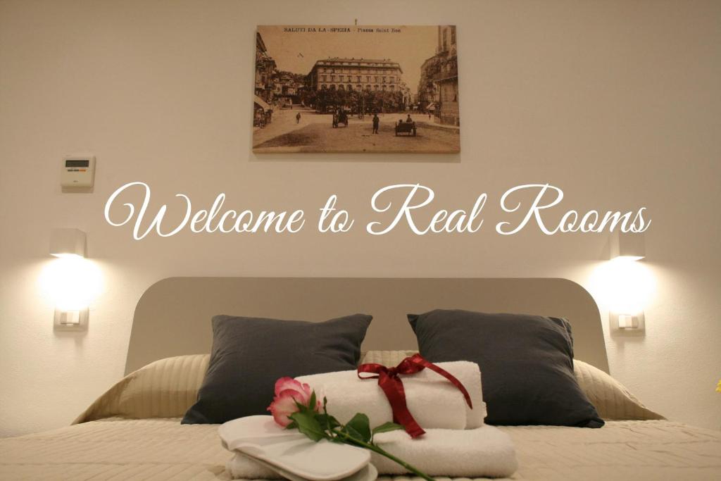 a sign that says welcome to real reasons above a bed at Real Rooms in La Spezia