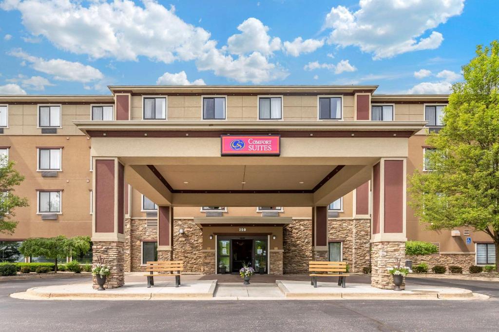 a building with two benches in front of it at Comfort Suites Grand Rapids North in Comstock Park