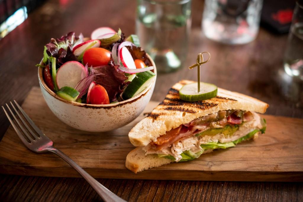 a sandwich and a salad on a cutting board with a fork at Kimpton Hotel Monaco Philadelphia, an IHG Hotel in Philadelphia