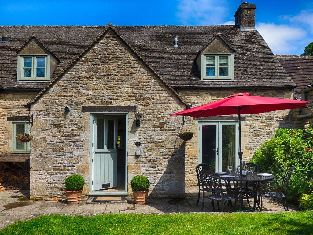a table with a red umbrella in front of a house at Greystones Cottage in Bourton on the Water